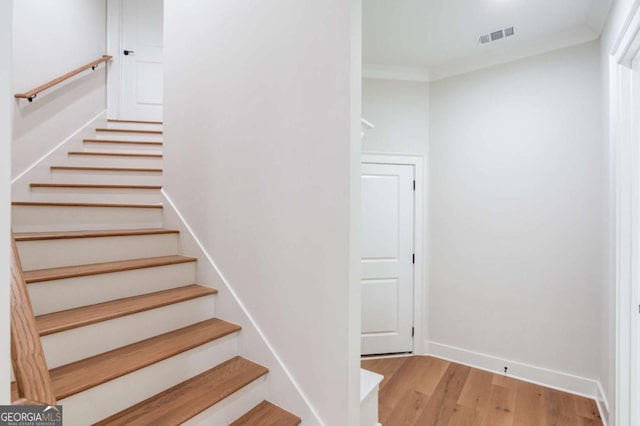 stairs featuring ornamental molding and hardwood / wood-style floors