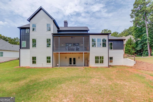 rear view of house with ceiling fan, french doors, a yard, and a sunroom