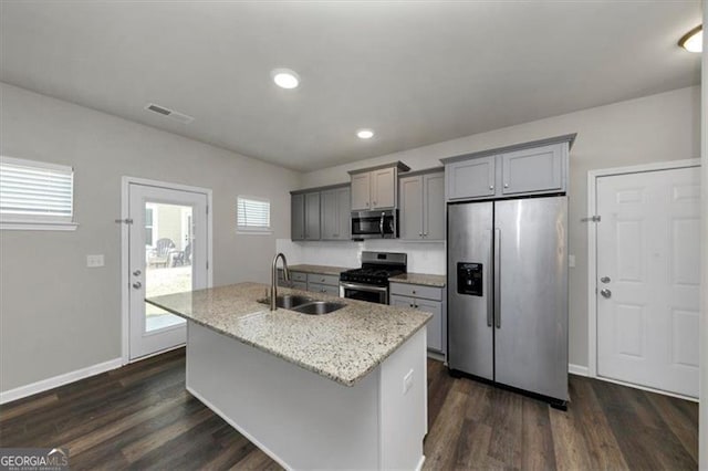 kitchen with stainless steel appliances, gray cabinets, a kitchen island with sink, and sink