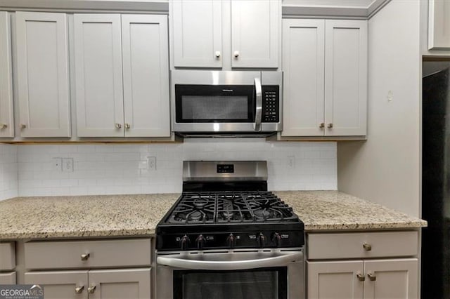 kitchen with light stone counters, appliances with stainless steel finishes, and decorative backsplash