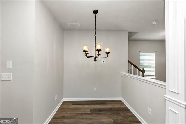 unfurnished dining area featuring an inviting chandelier and dark hardwood / wood-style floors