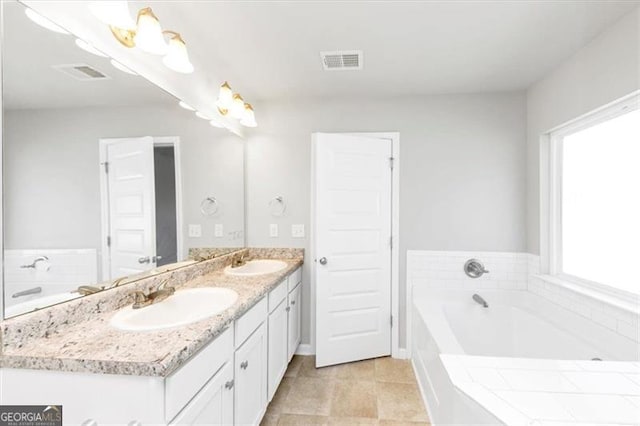 bathroom with tile patterned floors, vanity, and tiled tub