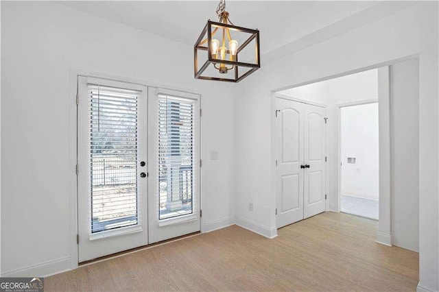 doorway to outside with light hardwood / wood-style flooring and an inviting chandelier