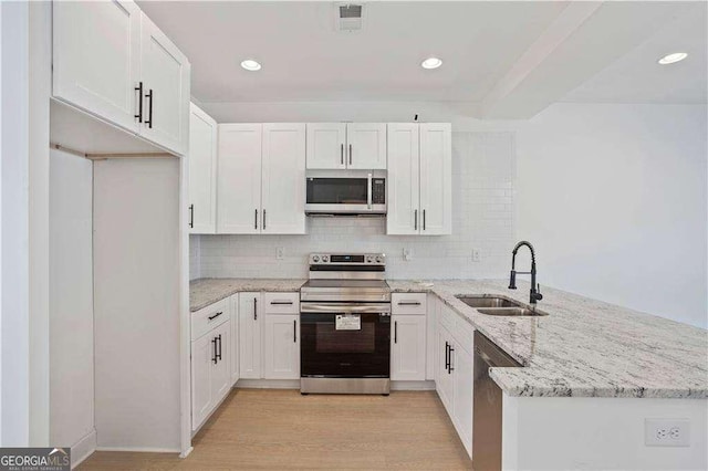 kitchen with light stone countertops, stainless steel appliances, white cabinetry, and sink