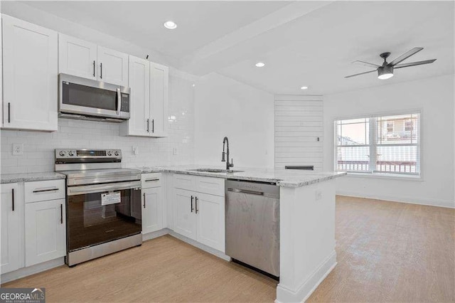 kitchen with ceiling fan, sink, white cabinetry, light wood-type flooring, and stainless steel appliances