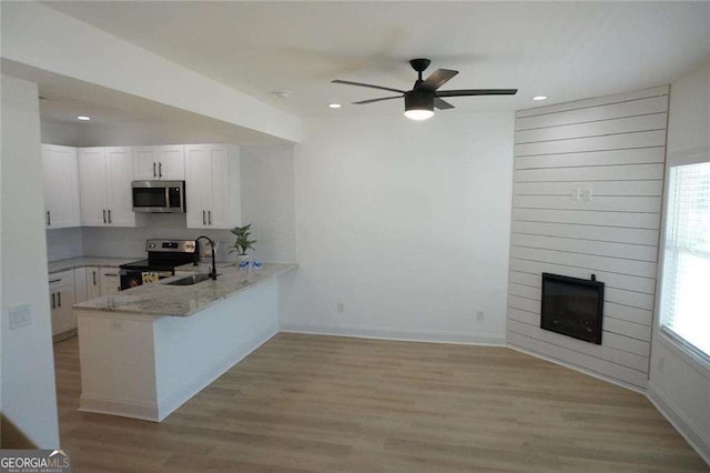 kitchen featuring kitchen peninsula, stainless steel appliances, white cabinetry, and light stone countertops