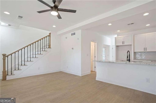 unfurnished living room with ceiling fan, sink, and light hardwood / wood-style flooring