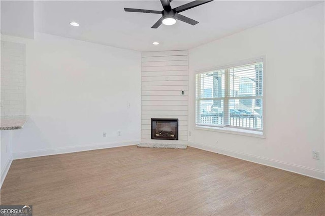 unfurnished living room with ceiling fan, light hardwood / wood-style floors, and a fireplace