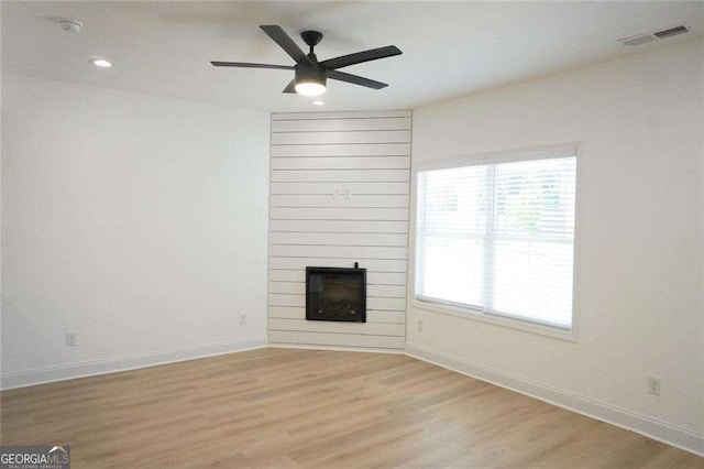 unfurnished living room featuring ceiling fan, light wood-type flooring, and a fireplace