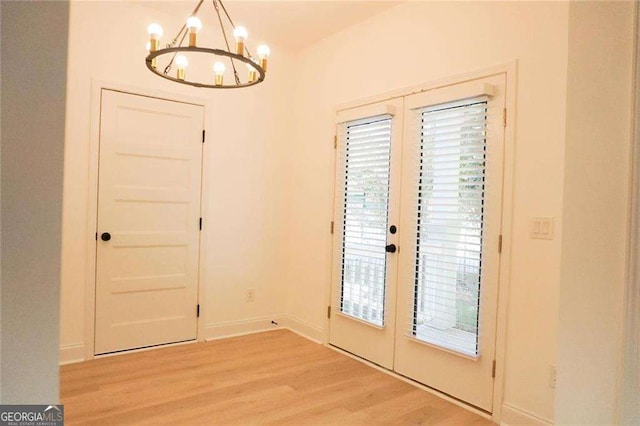 doorway with light hardwood / wood-style floors, a healthy amount of sunlight, french doors, and an inviting chandelier