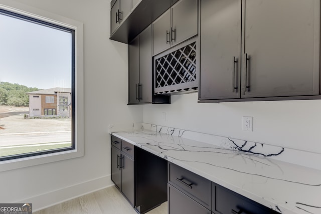 kitchen with light wood-type flooring, light stone countertops, and plenty of natural light