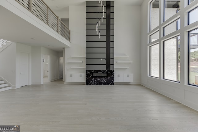 unfurnished living room with light hardwood / wood-style floors and a towering ceiling