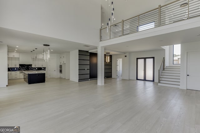 unfurnished living room featuring a towering ceiling and light hardwood / wood-style flooring