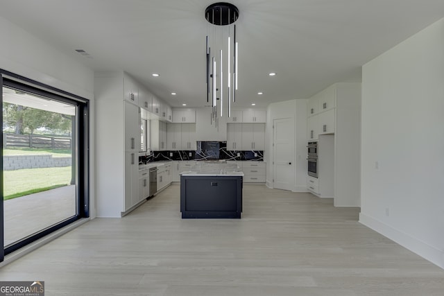 kitchen with light hardwood / wood-style floors, stainless steel appliances, hanging light fixtures, white cabinets, and a center island