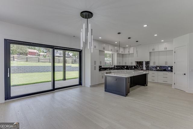 kitchen featuring pendant lighting, white cabinets, a center island, and light wood-type flooring