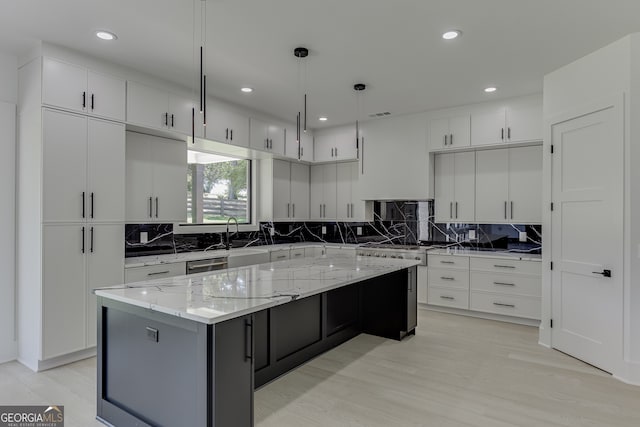 kitchen featuring decorative light fixtures, light hardwood / wood-style floors, white cabinetry, and a kitchen island