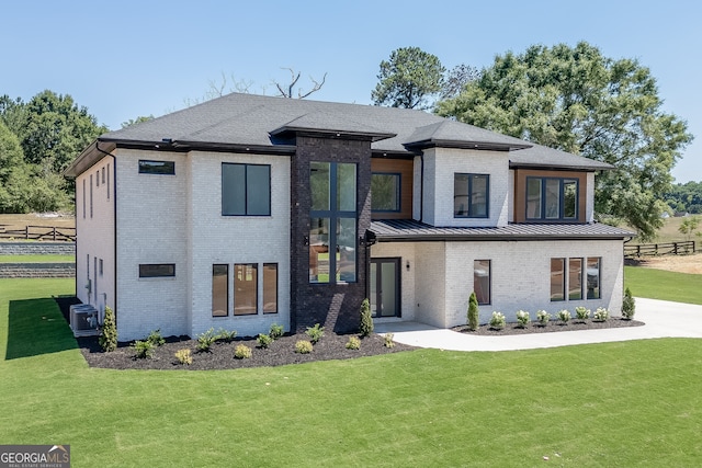 view of front of house featuring a front lawn and central AC