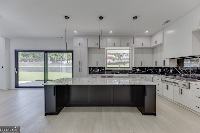 kitchen with stainless steel gas stovetop, pendant lighting, white cabinetry, and a large island