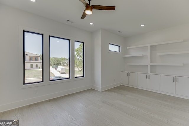 unfurnished room featuring ceiling fan, built in shelves, and light wood-type flooring