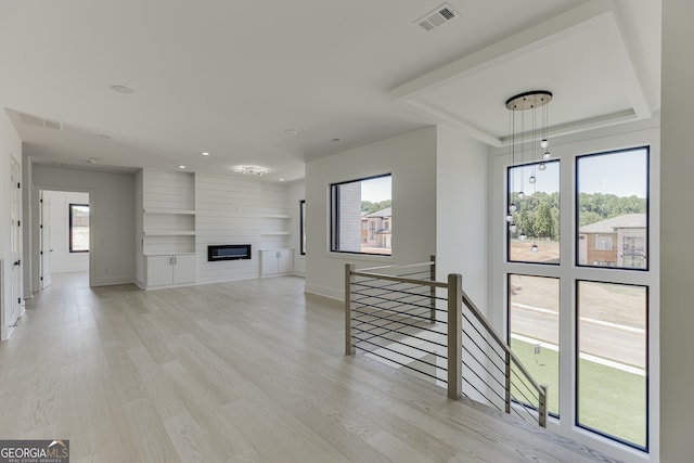 living room featuring a wealth of natural light, a large fireplace, and light hardwood / wood-style flooring