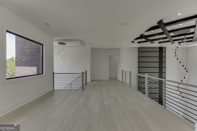 unfurnished room with beamed ceiling, coffered ceiling, and light hardwood / wood-style floors