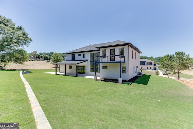 rear view of house with central AC unit, a patio, a balcony, and a yard