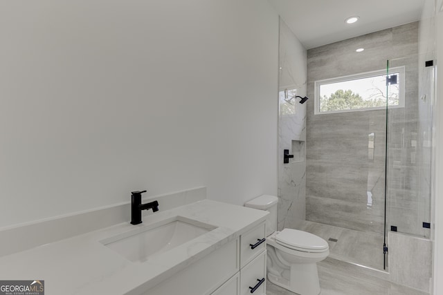 bathroom featuring toilet, vanity, and a tile shower