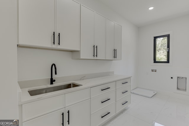 kitchen featuring light stone counters, sink, and white cabinets