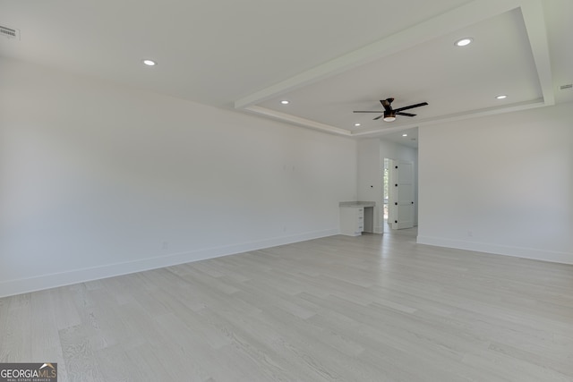 unfurnished room featuring ceiling fan, light hardwood / wood-style flooring, and a tray ceiling