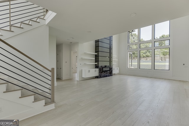 unfurnished living room with light hardwood / wood-style floors and a high ceiling