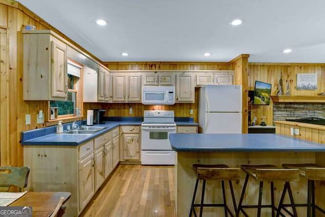 kitchen with light brown cabinets, sink, a center island, and white appliances