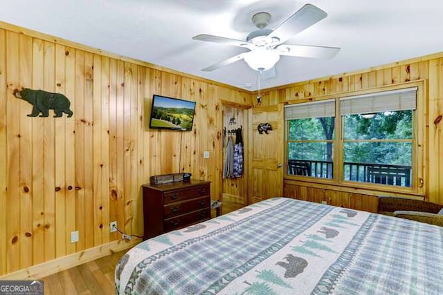 bedroom featuring wood walls, ceiling fan, and wood-type flooring