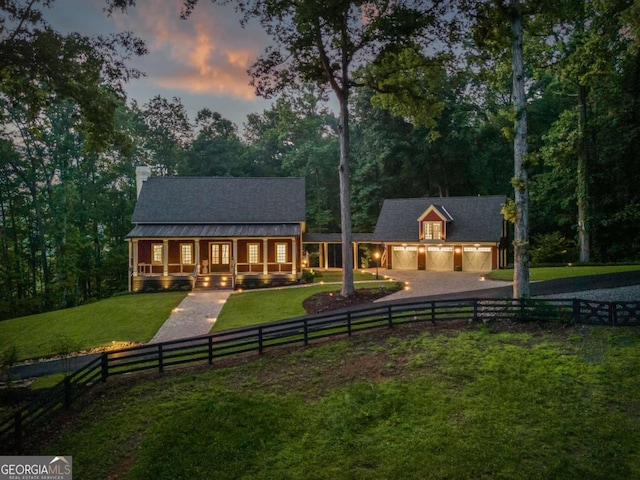 back house at dusk featuring a garage and a yard