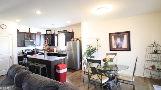 kitchen featuring sink, dark brown cabinets, dark hardwood / wood-style flooring, an island with sink, and stainless steel appliances