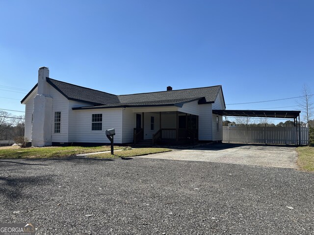 single story home with a carport, covered porch, and a front yard