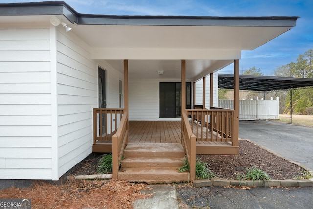 doorway to property featuring driveway, fence, and a carport