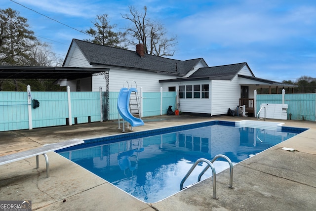 view of swimming pool with a fenced in pool, fence, a diving board, and a water slide