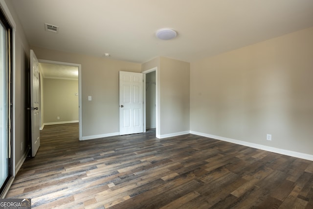 unfurnished bedroom with dark wood-style flooring, a closet, visible vents, and baseboards