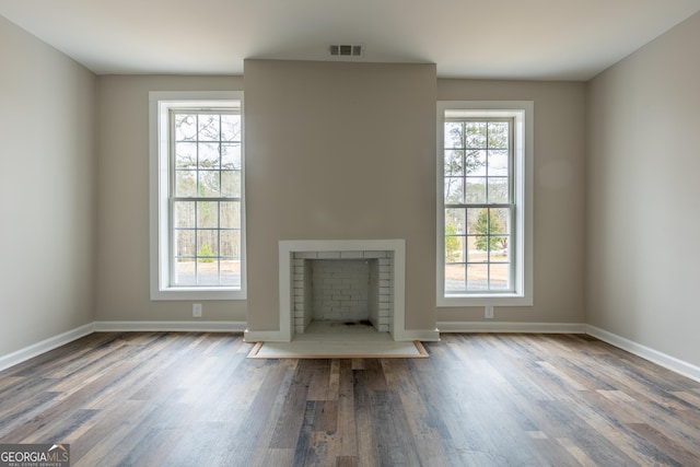 unfurnished living room with a fireplace, baseboards, and wood finished floors