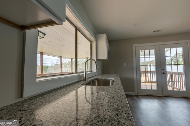 kitchen featuring light stone counters, a sink, visible vents, french doors, and dark wood-style floors