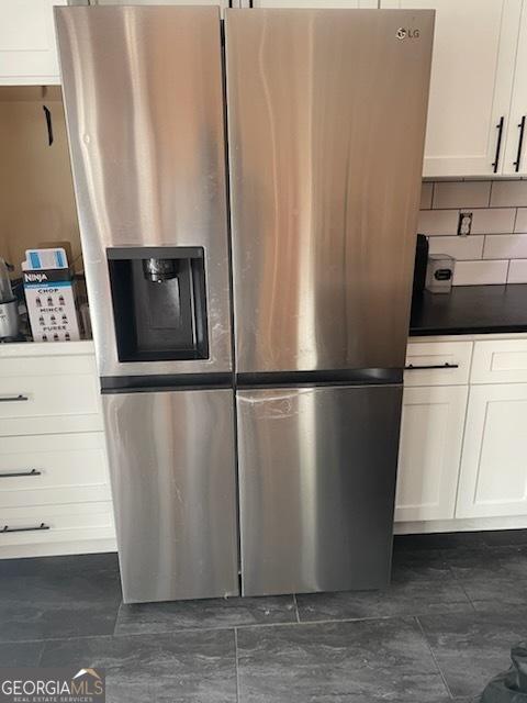 kitchen with stainless steel refrigerator with ice dispenser, white cabinets, decorative backsplash, and stainless steel fridge