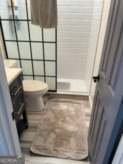 bathroom featuring tiled shower, toilet, and vanity