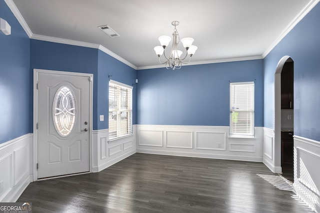 foyer with dark wood-type flooring, ornamental molding, and a notable chandelier