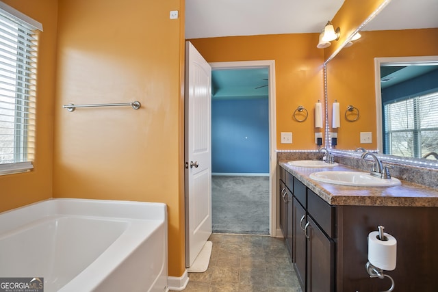 bathroom featuring a wealth of natural light, a bathtub, and vanity