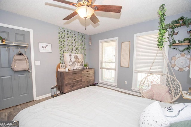 bedroom with light wood-type flooring, ceiling fan, and a textured ceiling