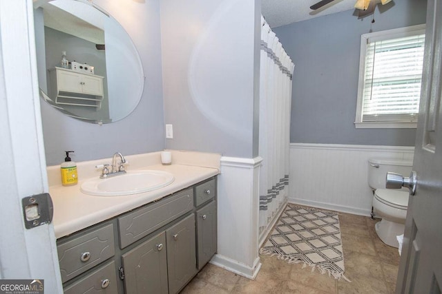 bathroom featuring toilet, vanity, and ceiling fan