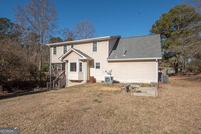 rear view of house featuring central AC unit and a lawn