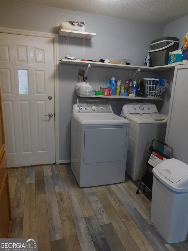 clothes washing area with hardwood / wood-style floors, washer and clothes dryer, and a textured ceiling