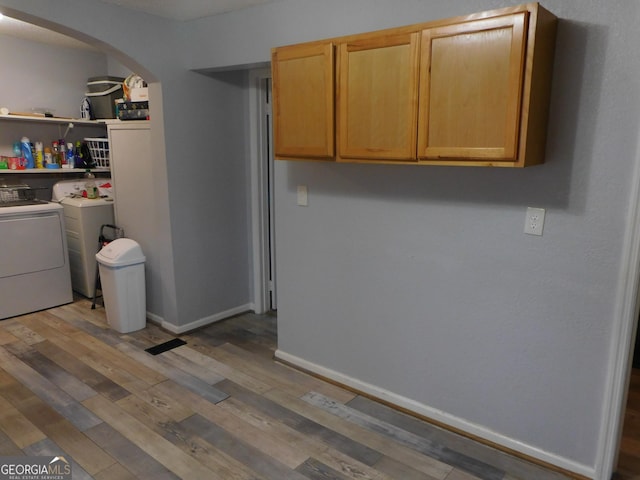 washroom with cabinets, washer and clothes dryer, and light hardwood / wood-style flooring