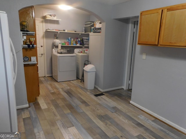 laundry room with washing machine and clothes dryer and light wood-type flooring